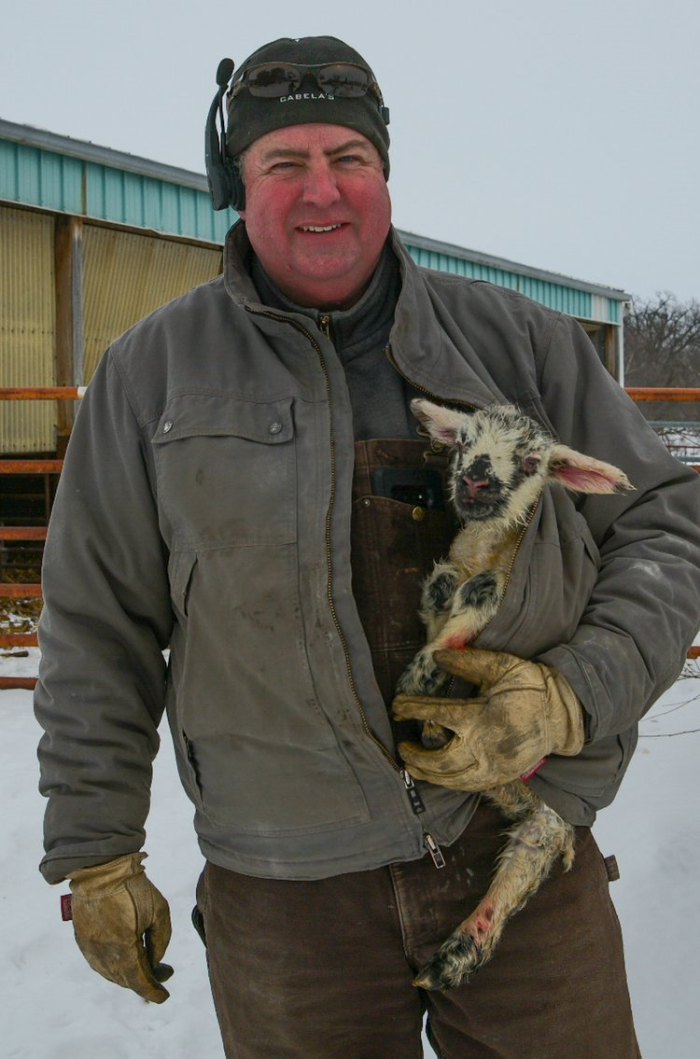 Dave Walton standing in winter, holding a baby goat